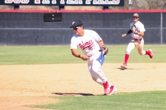Palomar baseball player in red and white has the baseball in his glove while he runs towards third base to make a force-out play.