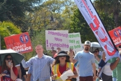 Protesters hold up signs while walking around campus during a rally on March 12, at the Palomar College San Marcos campus.