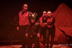 Beelzebub (Joshua DePaul) flanqueado por el elenco de demonios, con sus máscaras estilizadas y chalecos que acentúan el tono entre caricatura y crítica política de la obra. (Foto cortesía de Mariah Lambert)