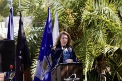 A blonde woman is standing behind the podium giving a speech.