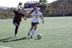 Palomar's Emma Gryn (#8) in black is running towards Grossmont's Aubrey Zerkle (#7) in white, attempting to retrieve the soccer ball.