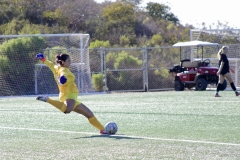 Nathalie Mancilla (#0) kicks the ball to her nearby teammates. Wearing a yellow uniform with blue gloves as she is the goalie for the Palomar Women's soccer team.