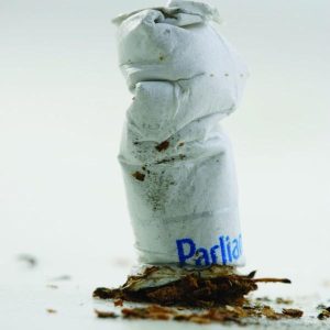 A crushed stub of cigarette lie vertically and slightly tilted to the left.