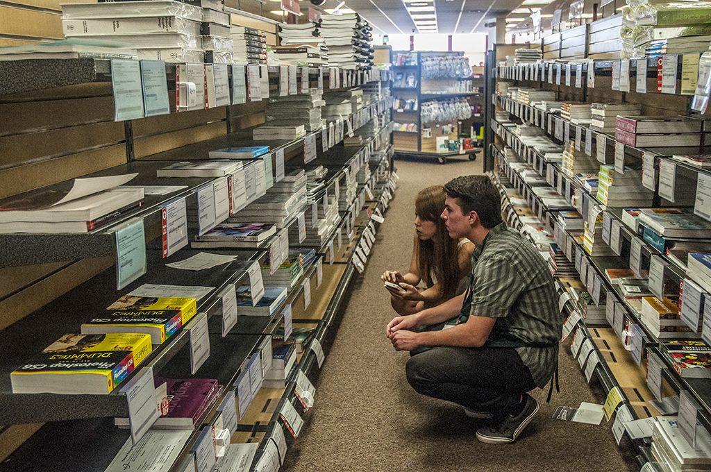 Sales Associate Ryan Pell (lower right) assists student Maika Takayabu (left) locate a book for her GCIP class at the Palomar College bookstore. On Sept. 16, 2013. (Lucas Spenser/The Telescope)