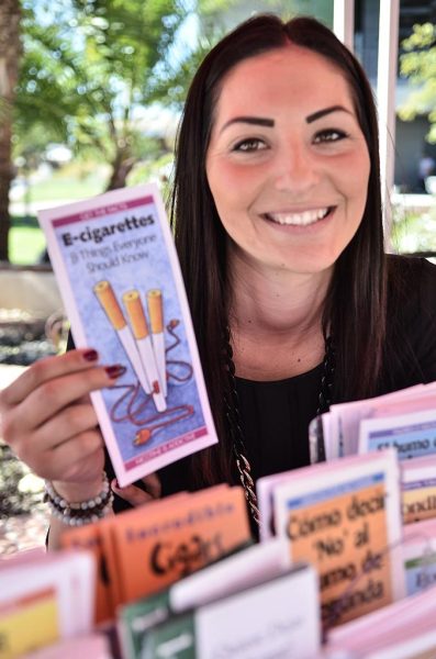 A female Palomar student holds an e-cigarette pamplet with a group of similar pamphlets in front of her.