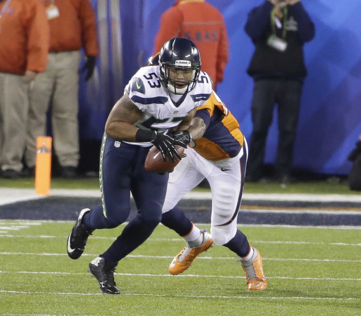 A football player tackles another player who is holding a football.