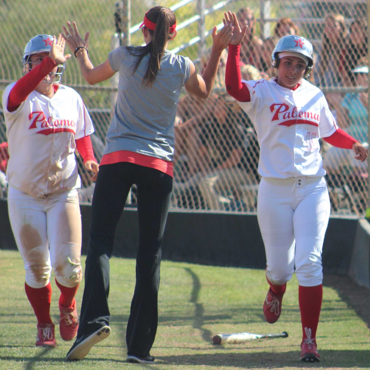 Palomar’s head softball coach Lacey Craft congratulates shortstop Kali Pugh (l) and outfielder Keilani ‘KK’ Fronda (r) after scoring on designated hitter Carlie Daniel’s RBI double against Riverside City College on April 15, 2014 at Palomar’s softball field. Fronda and Pugh both went 3-4 in the Comets’ 9-4 win over the Tigers in a rematch of the 2013 state title game when Palomar brought home a championship with a 7-2 win. (Scott Colson/The Telescope)