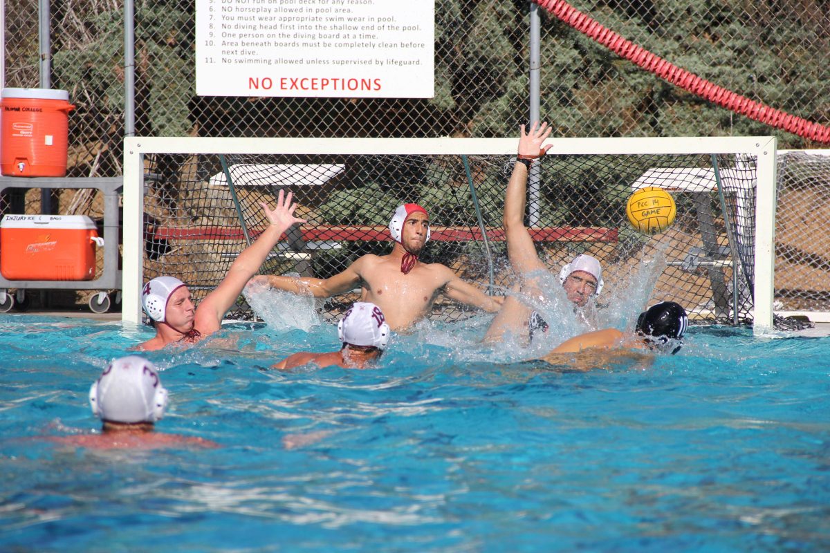 Several water polo players fight for the ball near a goal.