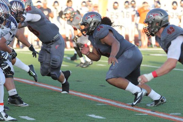 A Palomar football player rushes to tackle an opposing player with a team player on his sides doing the same thing.