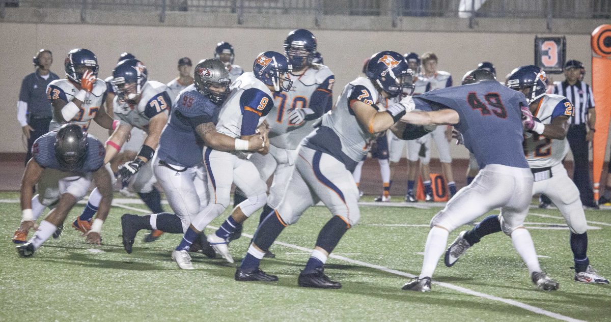 A Palomar football player tackles an opposing player from behind while other players tackle each other on all sides.