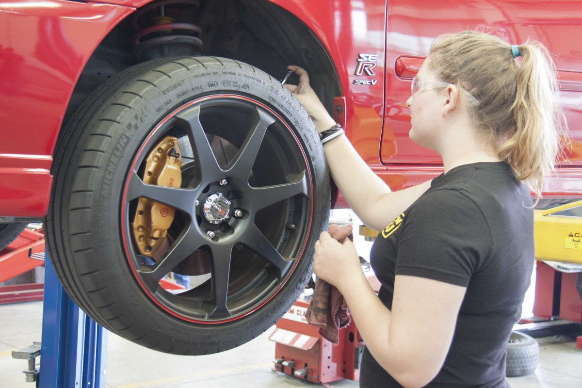 Kadi Donnelly, automotive technology student, performs maintenance on her car. (Stephen Davis/The Telescope)