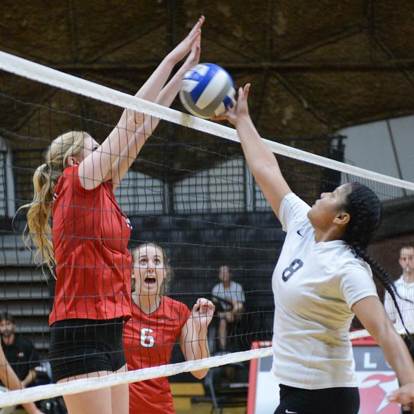 A female Palomar volleyball player blocks the ball from going over the net after the opponent hits it over.