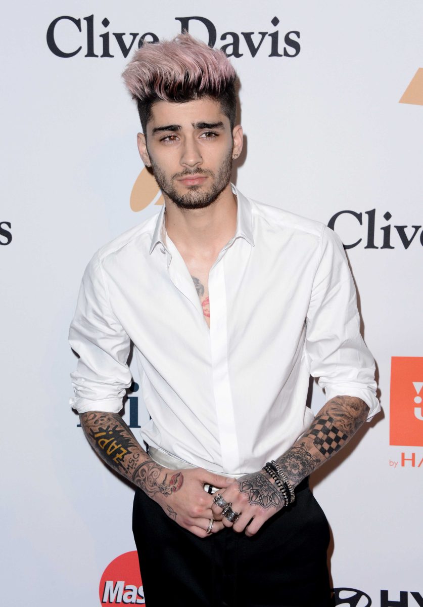 Zayn Malik of One Direction stand near a wall with the text "Clive Davis."