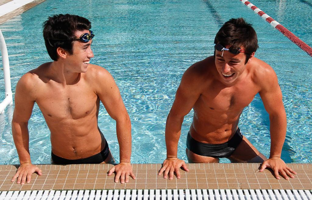 Two male Palomar swimmers smiles and climbs out of the pool.