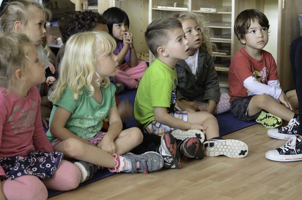 ECE (Early Childhood Education) Classroom. Five children sit and listen to their teacher read them a story before heading outside for recess. (Tracy Grassel/The Telescope)