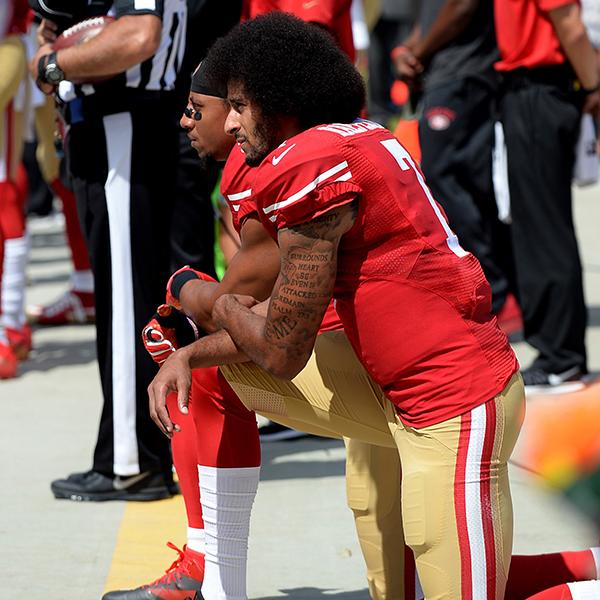 Colin Kaepernick and Eric Reid kneel on their left knee, profile shot.