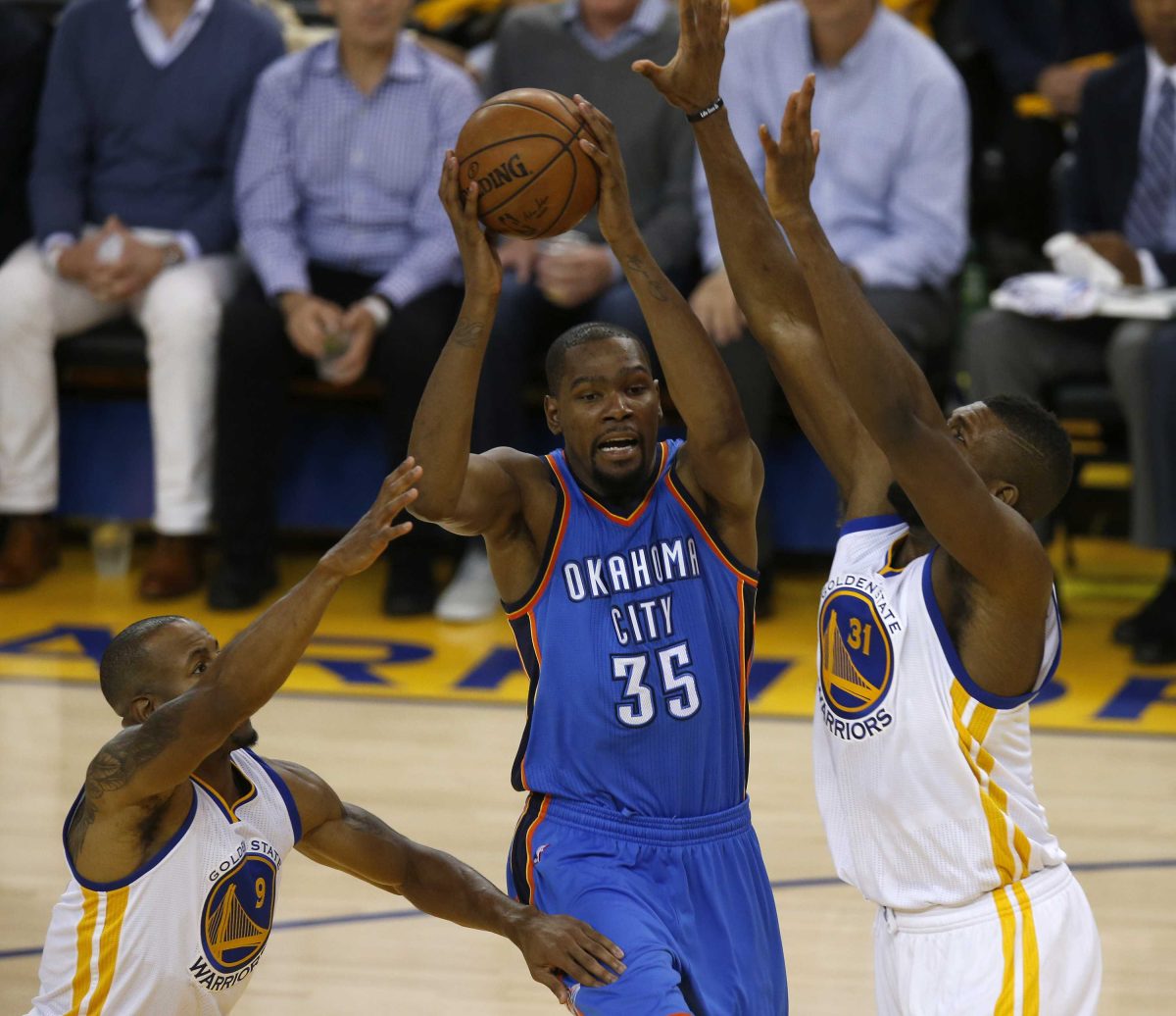 Two basketball players tries to block another player as the latter goes for a lay-up.