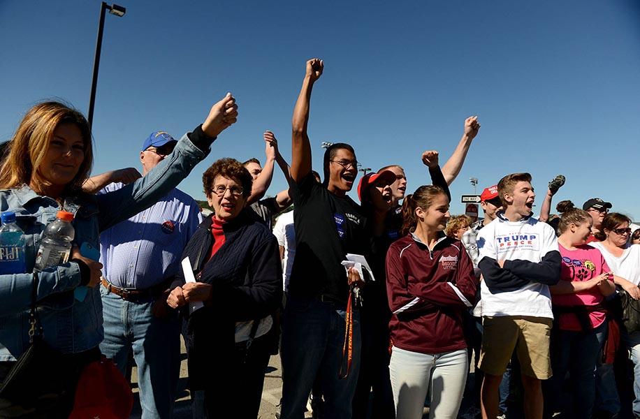 A group of people cheer and raise their fists in the air in support of Donald Trump.