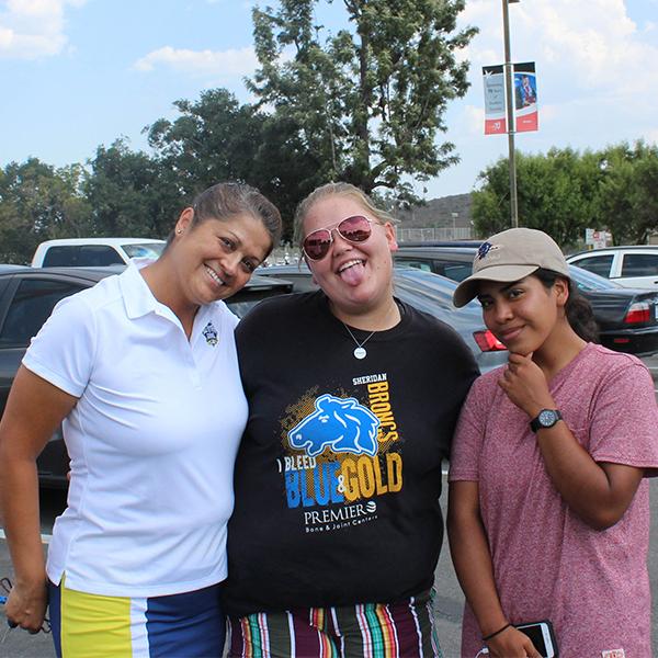 Three women from Palomar's women's golf team in plain clothes pose together at a parking lot.