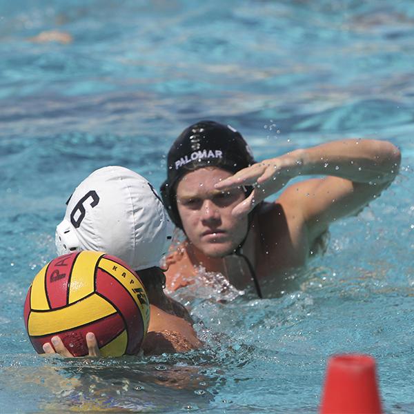 A male Palomar water polor player tries to block his opponent from passing the ball.