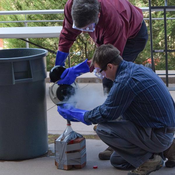 Professor of Geology Sean Figg and Assistant Professor of Astronomy Scott Kardel pour liquid nitrogen into the soda bottle at the Volcano Explosion event on Earth Science Day at the NS Building. Oct. 10, 2017. (Victoria Bradley/The Telescope)