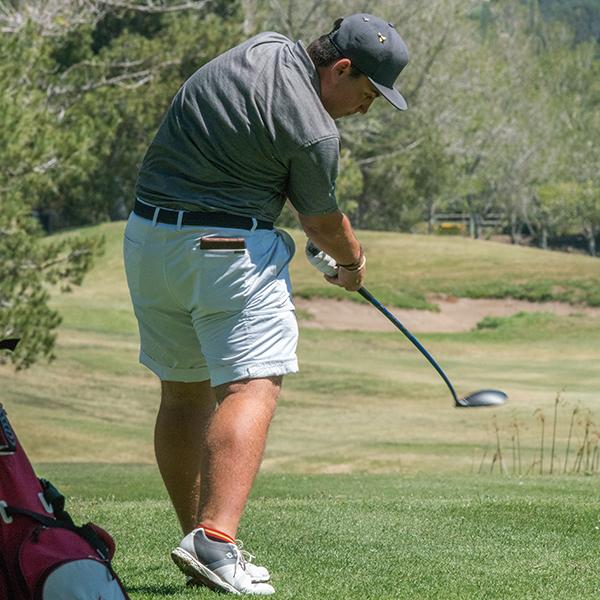 Palomar golfer Jaime Sanz swings his golf club and the ball flies to the right. He wears a gray cap, a gray shirt, and light gray shorts.