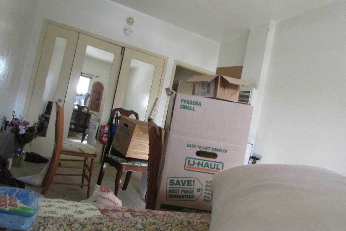 A stack of moving boxes and chair lay in a small apartment room.