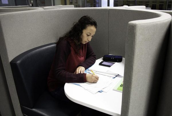 A female student writes on a piece of paper at a study booth at the Palomar library.