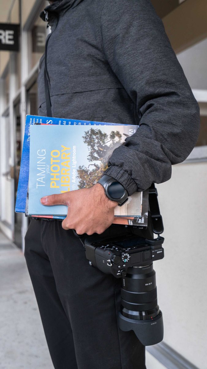 Palomar photography student Jason Hernanez shows off his textbooks and camera. The CALM (Comet's Affordable Learning Materials) program was implemented last year to assist students in decreasing textbook costs. (Elvin Diego/The Telescope)