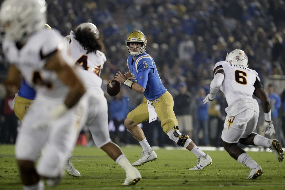 A football player runs to the left and holds a football in his right hand as he looks for someone to throw the football to.