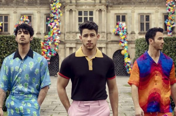 The Jonas Brothers stand side by side at a courtyard of an antique building.