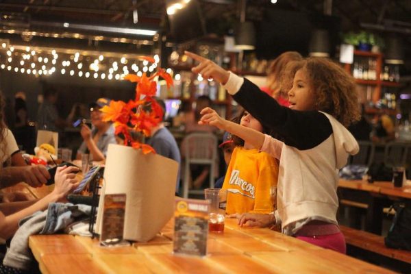 Several children point in front of them at a restaurant.