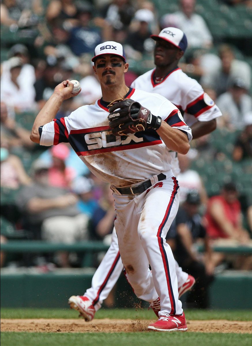 Chicago White Sox shortstop Tyler Saladino (18) throws a baseball with his right hand as a team player jogs behind him.