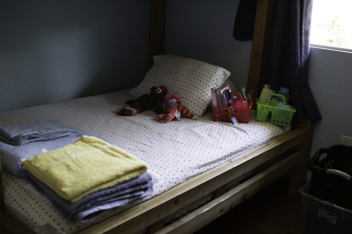 neatly made bed with toys and towels on top