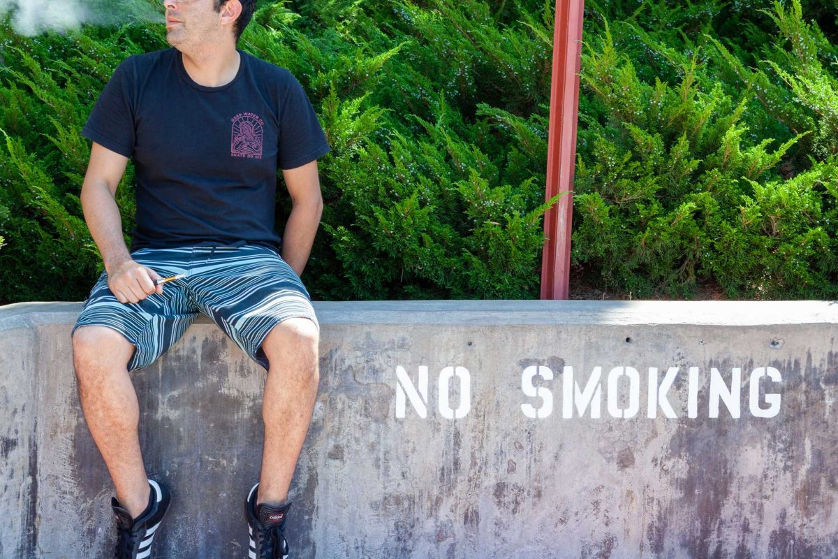 student vapes in front of a no smoking sign at Palomar College. Photo: Benjamin King/The Telescope.