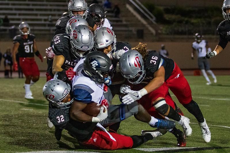 A group of football players tackle each other and fall down.