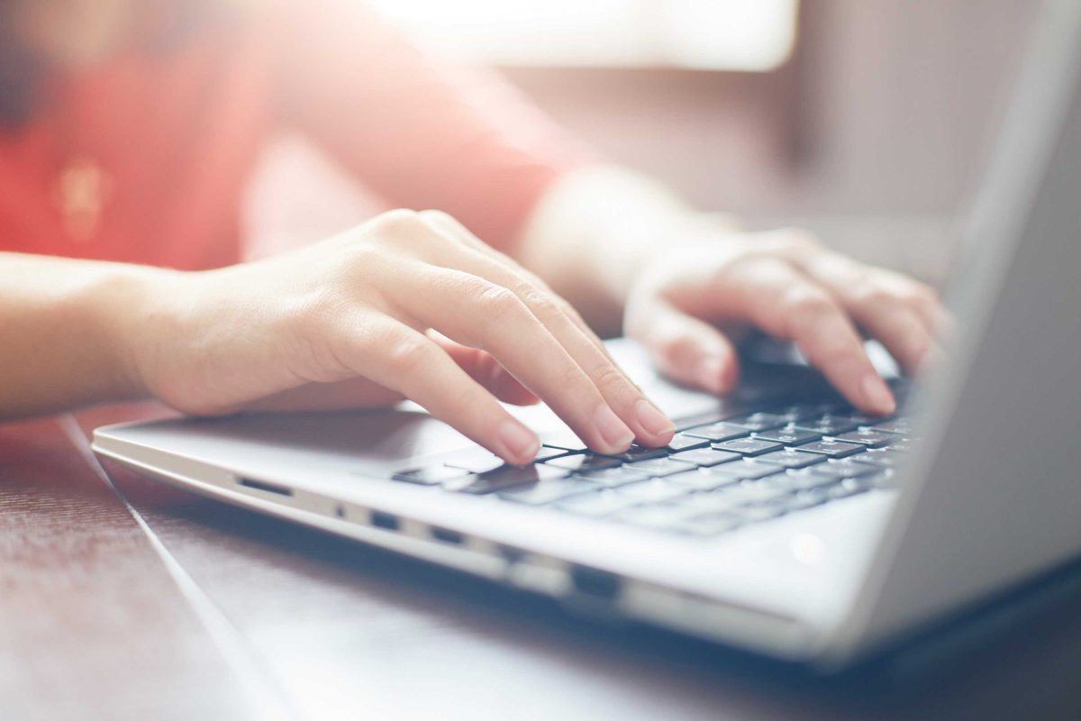 Hands typing on a laptop keyboard.