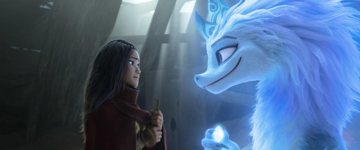 Animation shot of a young girl holding a book and wearing a dark red cloak. She looks at a young blue dragon wtih a thick mane. They smile at each other.