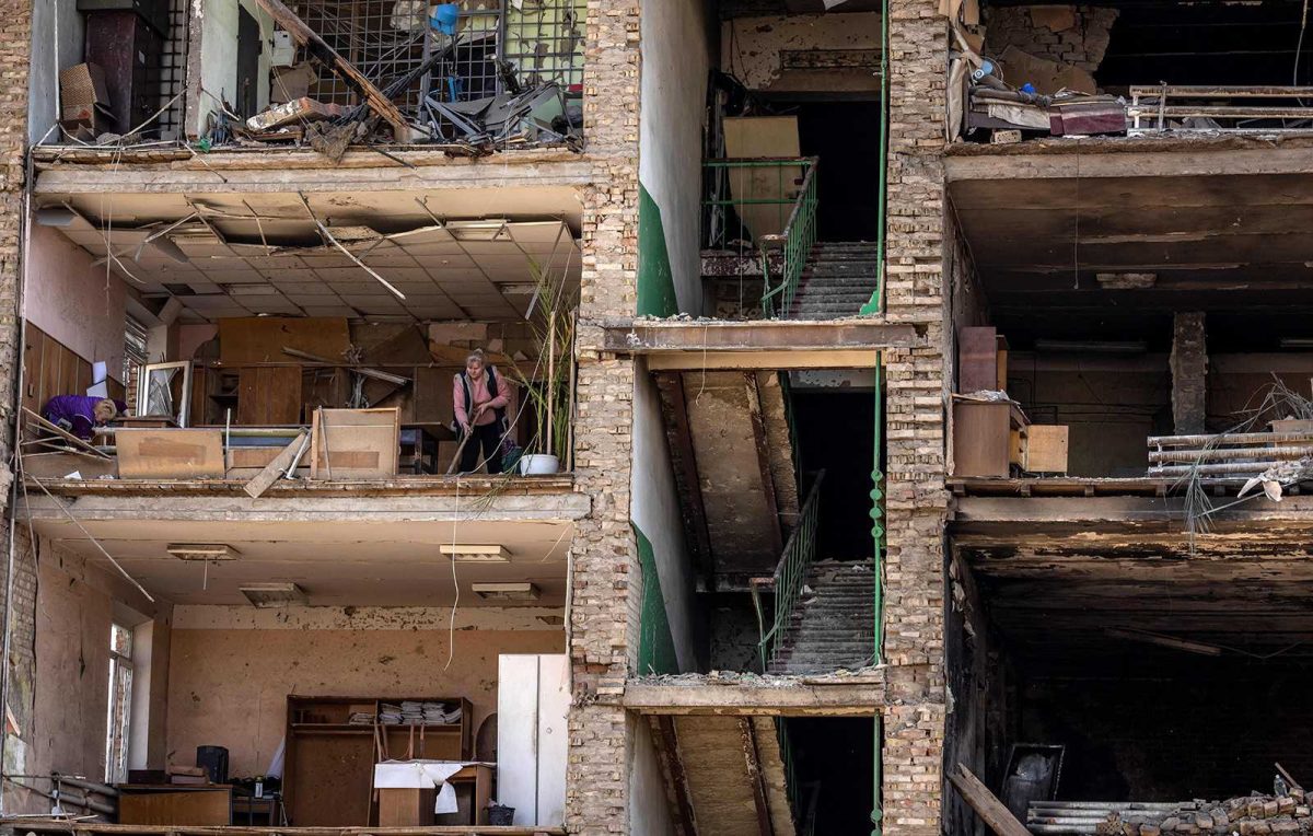 A building that was destroyed by bombs. Two women are inside one of the rooms.