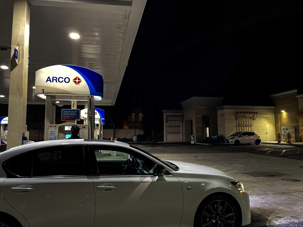 A car is next to a gas pump at an Arco gas station.