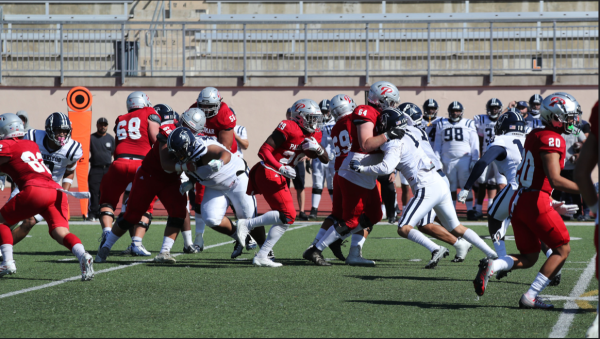 A group of football players tackle each other on the field.