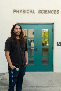 Professor Donyanavard (far left) stands outside one of the entrances to San Diego State’s Physical Sciences building.