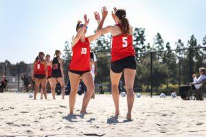 Palomar volleyball player Ashlynn Craven (5) high-fives a teammate at a beach volleyball match.