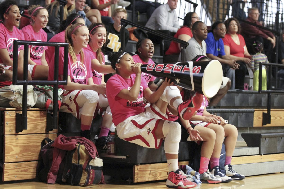 Palomar basketball player Keisha Cox leads the cheer at the men's basketball game in 2015. She holds a large, black megaphone with the word "Comets" on it.