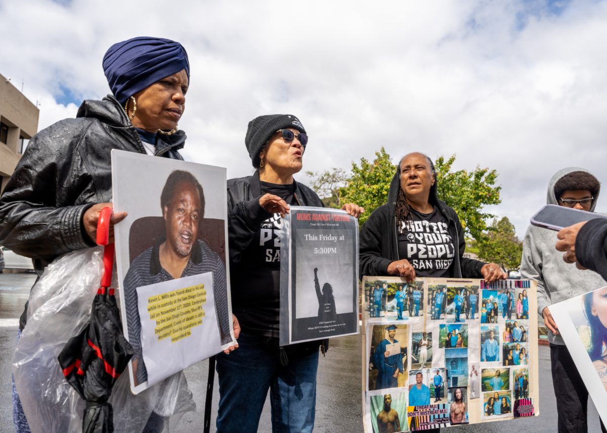 Three women protests while holding posters of those who died or were mistreated while under custody.