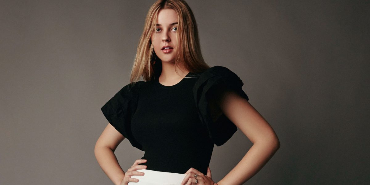 Palomar student Lindsey Rappaport wear a black top with large shoulder sleeves and a long white skirt. She stand with her arms akimbo.