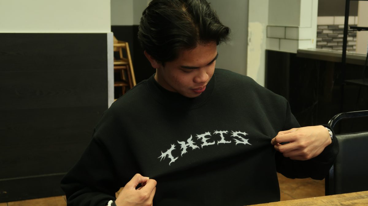 Tim Angeles shows the logo of his company, “Thesis,” on his black sweatshirt.