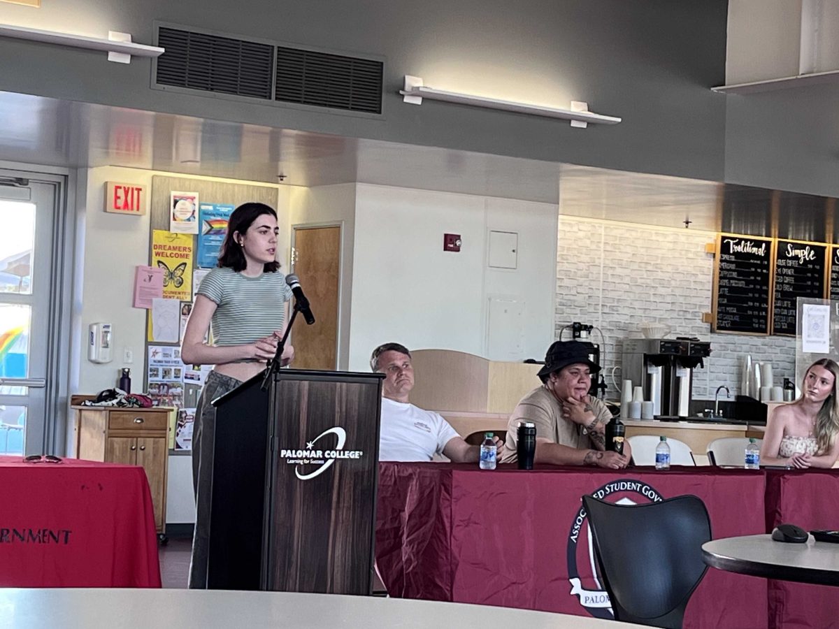 Safiya Swearingen, candidate for ASG President, gives a speech as candidates listen. At the table, from left to right: Derek Blevins (VP of Internal Affairs candidate), Sina Laei (VP of Events candidate), and Regan Barnum (Student Trustee candidate). Photo credit: Cynthia Cunningham