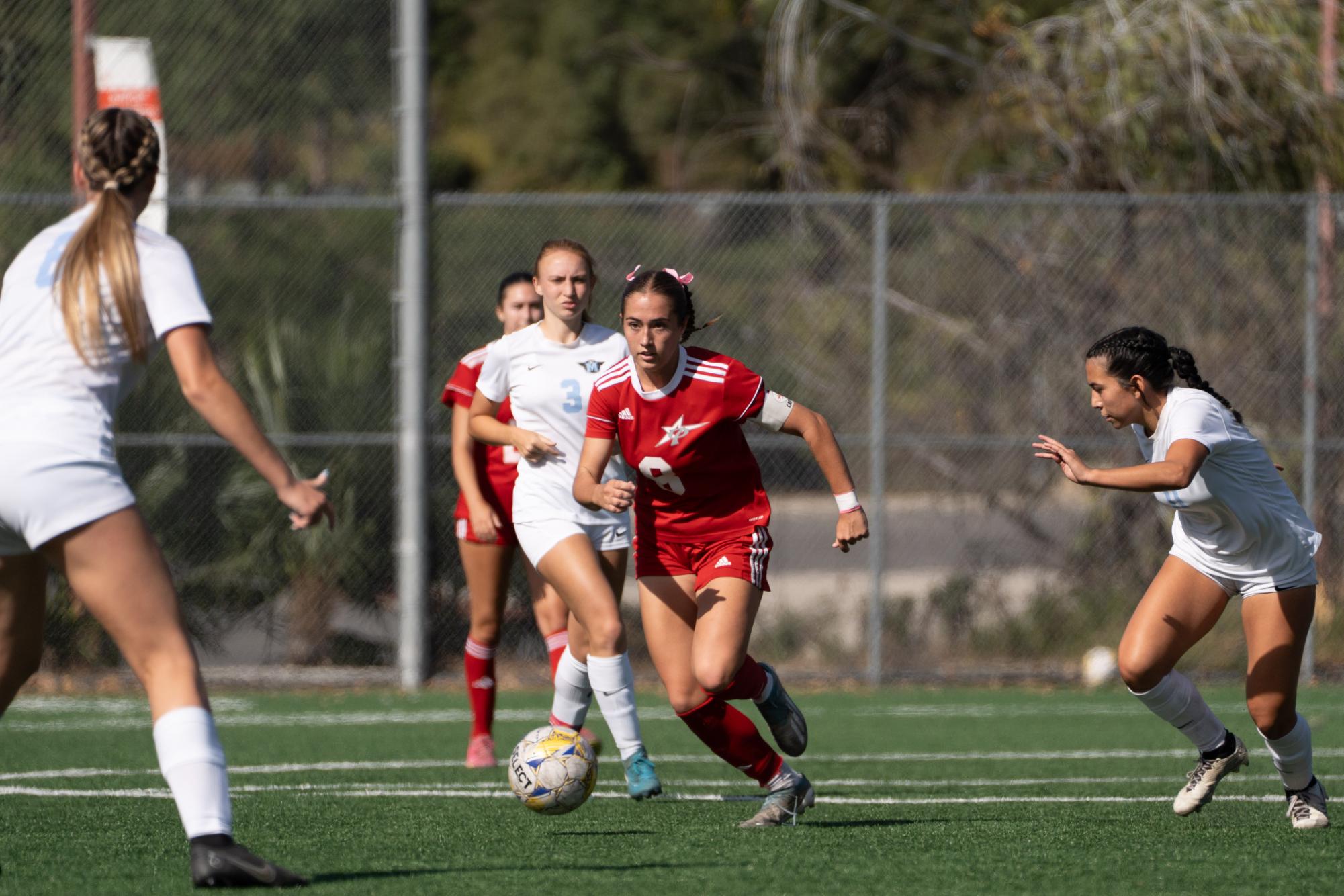 #8 Ashley Clark runs the ball up the field against multiple Miramar defenders.