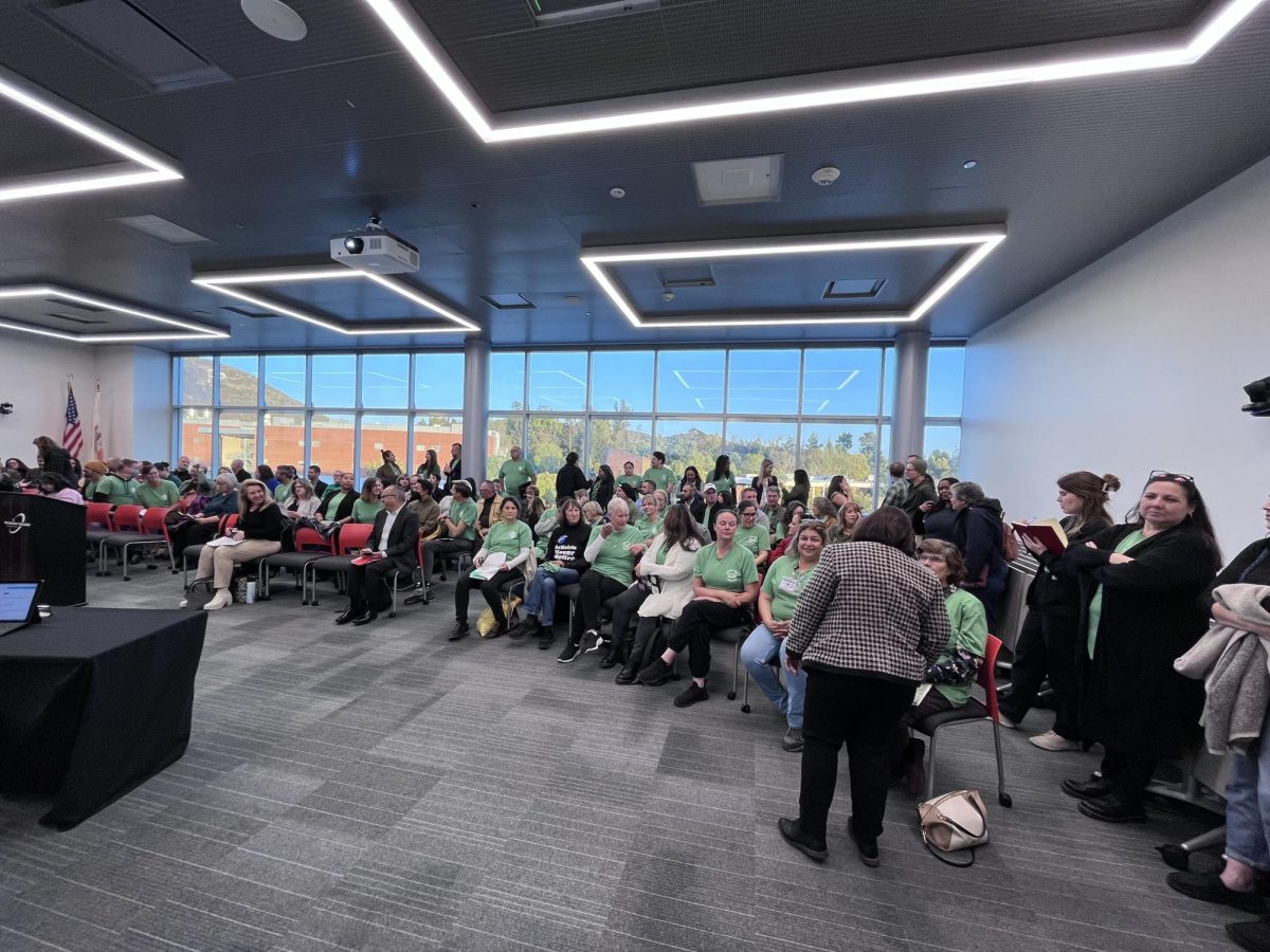 A large conference room with over 120 attendees. Many of the attendees wear matching green shirts.